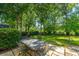 Backyard with patio featuring an outdoor dining set, lush lawn, and mature trees at 8725 Herons Walk, North Charleston, SC 29420