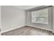 Bedroom with wood-look flooring, base molding, and a large window at 9016 Greenbriar Dr, Summerville, SC 29485
