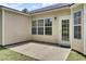 Concrete patio with beige siding, white framed windows, and a back door at 9016 Greenbriar Dr, Summerville, SC 29485