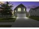 A two-story home with a two-car garage, well-lit windows, and neutral siding at dusk at 9680 Spencer Woods Rd, Ladson, SC 29456