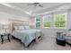 Bright bedroom featuring neutral tones, large windows, tray ceiling, and stylish furnishings at 105 Plowden Mill Ct, Summerville, SC 29485