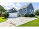 Blue home with attached garage and driveway, green lawn, and mature landscaping at 1070 Moss Grove Dr, Moncks Corner, SC 29461