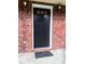 Close-up of a classic black front door framed by a red brick wall and vintage sconce lighting at 109 Ashdown Dr, Summerville, SC 29483
