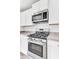 Stainless steel gas range and microwave are surrounded by white cabinets and gray counters at 113 Cozy Nest Way, Summerville, SC 29483
