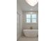Soaking tub with gold fixtures, set beneath a window, complementing the room's clean, white design at 14 55Th Ave, Isle of Palms, SC 29451
