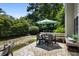 Outdoor patio featuring a dining table with umbrella and a cushioned bench, surrounded by lush greenery and a patterned rug at 1406 Oaklanding Rd, Mount Pleasant, SC 29464
