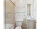 Bright bathroom featuring a tiled shower, glass shelves, and a vanity with a marble countertop at 2 Bedons Aly, Charleston, SC 29401