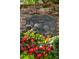 Charming outdoor decor features a cherub plaque nestled amid red flowers and lush greenery on a brick wall at 2 Bedons Aly, Charleston, SC 29401