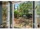 View from inside the house looking out to a brick patio with seating surrounded by lush landscaping at 22 Lamboll St # C, Charleston, SC 29401