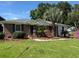 Charming brick home with a well-manicured lawn and mature landscaping, including palm trees at 2456 Lantern St, Charleston, SC 29414