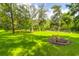 Lush green backyard with a large fire pit surrounded by mature trees at 2494 Cape Rd, Johns Island, SC 29455