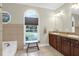 Well-lit bathroom featuring dual sink vanity, framed window, and tile flooring, offering a serene and functional space at 2494 Cape Rd, Johns Island, SC 29455