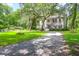 Two-story home featuring a gravel driveway, lush lawn, and a charming porch, all framed by mature trees at 2494 Cape Rd, Johns Island, SC 29455