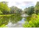 Beautiful pond view with a fountain surrounded by trees with a house in the distance at 2494 Cape Rd, Johns Island, SC 29455