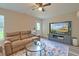 Cozy living room featuring a comfortable brown sofa, ceiling fan, and entertainment center with large screen TV at 2538 Wayne Scott Ct, Charleston, SC 29414