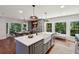 Spacious kitchen with a gray island, farmhouse sink, and a dining area with large windows offering wooded views at 338 Mcclellan Ave, McClellanville, SC 29458