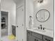 Well lit bathroom with a speckled countertop, a round mirror, dark gray cabinets, and a view to an adjacent room at 360 Parish Farms Dr, Summerville, SC 29486