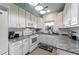 Bright kitchen features white cabinets, granite countertops, stainless appliances and tile flooring at 4765 Arco Ln, North Charleston, SC 29418