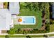 Aerial view of a house with a grey roof, green lawn, tall hedges, paved patio, and rectangular pool at 566 Wading Pl, Daniel Island, SC 29492