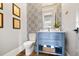 Chic powder room featuring patterned wallpaper, blue vanity, gold fixtures, and decorative wall art at 566 Wading Pl, Daniel Island, SC 29492