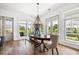 Bright dining room features hardwood floors, modern chandelier, and many windows with beautiful backyard views at 566 Wading Pl, Daniel Island, SC 29492