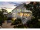 Charming two-story home showcasing white exterior paint, a covered porch, and lush landscaping at dusk at 566 Wading Pl, Daniel Island, SC 29492