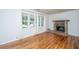 Light-filled living area featuring hardwood floors, brick fireplace, and large windows with bright white curtains at 734 Waterloo St, Charleston, SC 29412