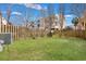 Spacious, grassy backyard enclosed by a wooden fence with mature trees and buildings in the background at 9024 Parlor Dr, Ladson, SC 29456