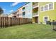 Backyard featuring a wooden fence, grassy area and colorful buildings with balconies under a blue sky at 9024 Parlor Dr, Ladson, SC 29456