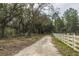 A dirt road meanders past a white fence in a wooded area, suggesting a peaceful, rural setting for a home at 104 Limpkin Ln, Summerville, SC 29483