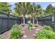 Well-manicured backyard with a decorative bench, lush greenery, dark fencing, and palm trees at 1100 Griswold St, Mount Pleasant, SC 29466