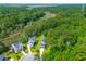 An aerial view shows the house nestled among dense green trees in a neighborhood near the coast at 129 Martins Point Dr, Wando, SC 29492