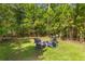 Backyard fire pit with Adirondack chairs surrounded by mature trees, offering a private retreat at 129 Martins Point Dr, Wando, SC 29492