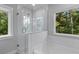 Bright bathroom featuring a glass-enclosed shower and a luxurious soaking tub beneath a large window with a wooded view at 129 Martins Point Dr, Wando, SC 29492