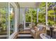 A screened porch with a comfortable armchair, wooden floor, and view of trees creating an inviting outdoor space at 129 Martins Point Dr, Wando, SC 29492