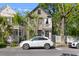 Charming two-story home with white car parked, surrounded by lush trees and a white picket fence at 176 Smith St, Charleston, SC 29403