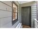 Close-up of home exterior with gray siding, a dark front door and a small bench at 176 Smith St, Charleston, SC 29403
