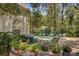 Lush backyard with stone patio, comfortable seating, vibrant flowers, and sparkling pool at 208 Sumter Ave, Summerville, SC 29483
