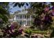Beautiful white home with a welcoming porch, surrounded by vibrant azaleas and greenery at 208 Sumter Ave, Summerville, SC 29483