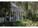 Charming front porch of a white cottage, adorned with hanging flower baskets at 208 Sumter Ave, Summerville, SC 29483