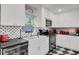 Stylish kitchen featuring white cabinets, black countertops, and unique black and white backsplash at 208 Sumter Ave, Summerville, SC 29483