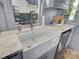 Sunlit kitchen with a farmhouse sink, marble countertops, and stainless steel dishwasher at 208 Sumter Ave, Summerville, SC 29483