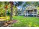 Spacious backyard with lush lawn, mature palm trees, and porch, perfect for outdoor living at 2228 Daniel Island Dr, Charleston, SC 29492
