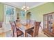 Cozy dining room with green walls, wood table and chairs, and a charming chandelier at 2228 Daniel Island Dr, Charleston, SC 29492