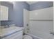 A well-lit bathroom featuring white tiled shower and tub with a white vanity and sink at 227 Grace St, Walterboro, SC 29488