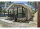 Inviting covered porch with brick base and vibrant green door, set amidst lush greenery at 227 Grace St, Walterboro, SC 29488
