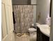This bathroom features patterned shower curtain, a single vanity with dark cabinets, decorative accents, and light wood floors at 306 Park St, Saint George, SC 29477