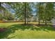 Backyard view featuring mature trees, a manicured lawn, and a charming home at 309 Pinopolis Park Dr, Moncks Corner, SC 29461