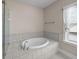 A white, tiled bathtub with a shower head and a window at 4140 Home Town Ln, Ravenel, SC 29470