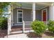 Charming front porch with wood floors, white columns, blue ceiling and red door at 4140 Home Town Ln, Ravenel, SC 29470